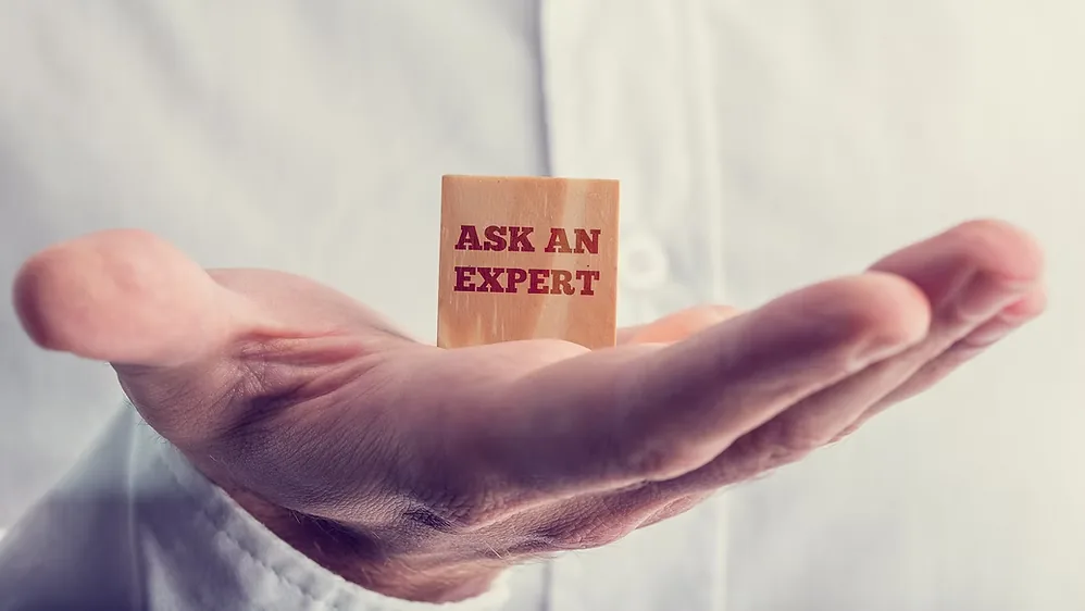 Mão estendida segurando um bloco com a inscrição ask an expert